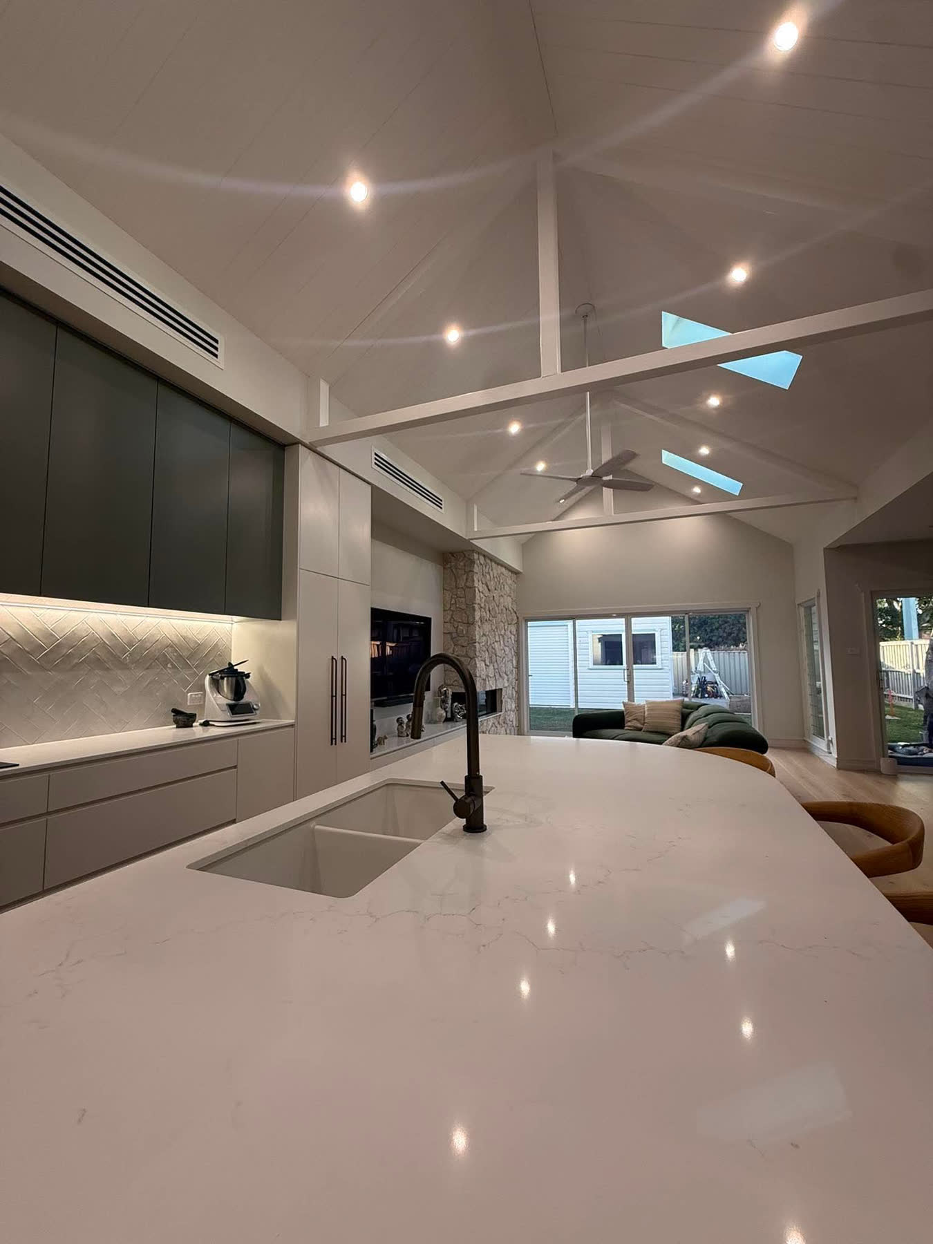 Vaulted-ceiling kitchen and living space with recessed downlights, pendant light and ceiling fan installed by NeoGen Electrical